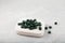 Pile of green pills on white wooden podium. Selective focus, Copy space. Natural Chlorella and Spirulina in tablet form
