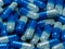 Pile of half-blue transparent pill capsules for background