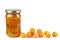 Pile of half-dried yellow cherry plums and glass jar with jam isolated on the white