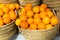 Pile of juicy oranges in wicker baskets on market counter