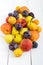 A pile of juicy summer fruits on white wooden background plums, apricots, pears.