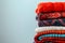 Pile of knitted sweaters and cozy scarves on solid background with copy space, Stack of clothes