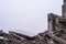 A pile of large concrete fragments against the background of the remains of the building and the gray sky. Background