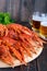 A pile of large crawfish on a wooden tray, glasses with beer