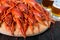 A pile of large crawfish on a wooden tray, glasses with beer