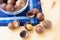 Pile of macadamia nuts in whole kernels and half opened on wooden background with darl blue napkin and translucent bowl.