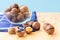 Pile of macadamia nuts in whole kernels and half opened on wooden background with darl blue napkin and translucent bowl. Seeds of