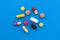 A pile of medicines of different sizes and colors lie on a blue background.