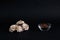 A pile of meringues and a bowl of cinnamon powder  on black background