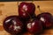 Pile of moldy cherries on wooden desk, black background