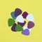 Pile of multicoloured guitar picks isolated on a yellow background. Minimal music concept