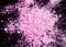 Pile of natural colored pigment powder. Pink powder particles splatter on black blackground