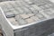 Pile of new grey paving stones on wooden pallet fixed with stretch wrap. Blocks texture, background, close-up.