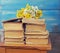 Pile of old books with a bouquet of yellow flowers