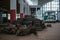 A pile of old car parts and tires in a large garage building with a green bus on a bokeh background