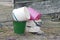 A pile of old colored plastic and metal buckets stand on the ground