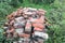 Pile old, cracked, burnt, broken bricks lie on green flowering lawn. Environmental pollution