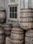 Pile of old wooden barrels by a wall.