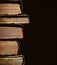 A pile of an old yellowed with age books on the black background