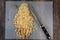 Pile of partially chopped raw walnuts on a plastic cutting mat with a chefâ€™s knife