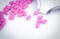 Pile of pink tablets pill on white background near stainless steel drug tray. Ibuprofen 400 mg. Painkiller medicine for headache