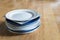 Pile of random white and blue plates on a wooden table