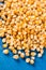 Pile of raw popcorn above blue wooden background with copy space