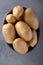 Pile of raw potatoes in the bowl on concrete background