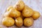 Pile of raw potatoes at wooden table in home kitchen