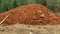 Pile of red earth on green bush background