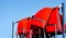 Pile of red lifejackets used by water  rescuers sitting on a rake   near beach during summer season  against blue  sky