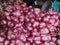 Pile of Red Shallots for Sale with Blurred Weighing Scale on Background