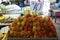 Pile of ripe sweet reddish rambutan fruit with pliable green hair in local market atmosphere