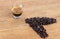 Pile of roasted organic brown coffee beans with a cup of hot espresso coffee on a rustic wooden table from a high angle view