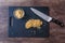 Pile of rough chopped walnuts on a black cutting board, fine chopped walnuts in glass bowl, chef knife