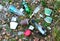 A pile of rubbish on the ground from plastic bottles, coffee paper cups, fast food packaging. Thrown glass bottle from alcohol in