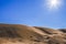 Pile of sand against blue sky and bright sun