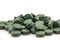 Pile of spirulina powder and capsules on white background