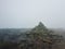 Pile of stones on the muddy ground surrounded by mist on the top of Hoverla peak in Carpathian Mountains