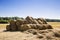 A pile of straw rolls stacked on the meadow. Field with dry yellow grass in summer day