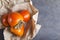 Pile of tasty persimmon on the brown craft paper for food, grey table.Empty space for text