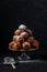 A pile of traditional oliebollen (Dutch dough firtters) on a glass stand on black background