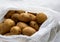 A pile of unwashed potatoes lies in a bag