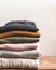 Pile of varicolored autumn clothes on wooden background, sweaters, knitwear, copy space