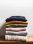 Pile of varicolored autumn clothes on wooden background, sweaters, knitwear, copy space