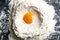 Pile of wheat flour and and egg yolk on a granite kitchen counter. Top views, close-up