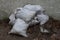 A pile of white garbage bags on the ground near the fence