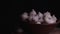 Pile of whole bulbs of garlic in ceramic bowl on table. Harvest of unpeeled vegetables on black background.