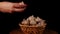 Pile of whole bulbs of garlic in a wicker basket on table. Woman's hand puts the garlic in a wicker basket.