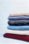Pile of wool sweaters and knitted winter clothes on blue wooden background. Copy space for text.